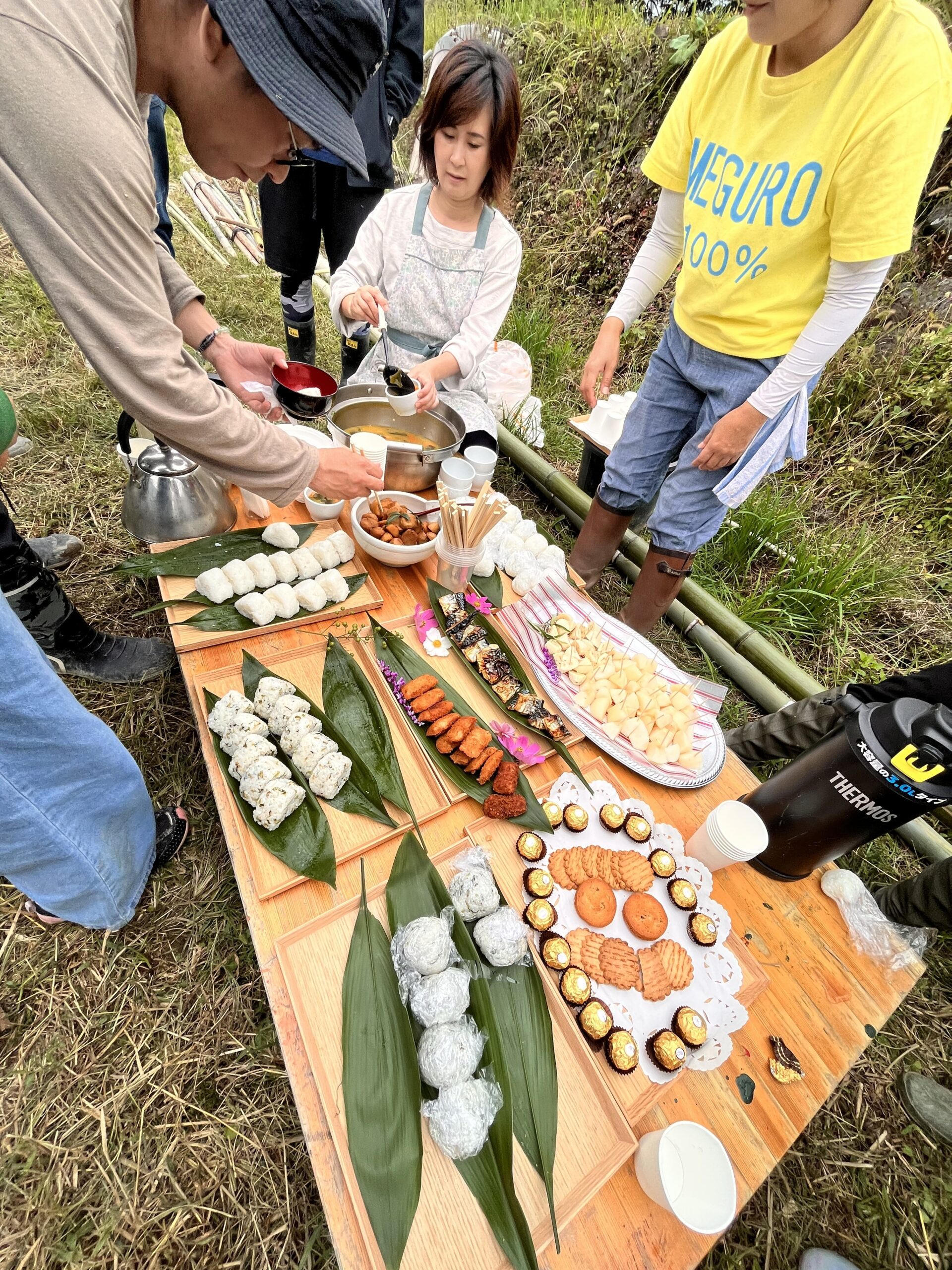 おにぎりや料理が並ぶ食卓で、汁物を取り分ける様子